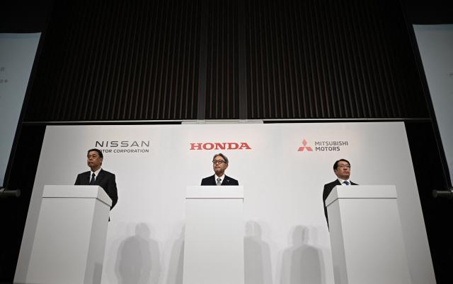 (L to R) Makoto Uchida, President and CEO of Nissan motor corporation, Toshihiro Mibe, President and Representative Executive Officer of Honda, and Takao Kato, President and CEO of Mitsubishi Motors attend a joint press conference in Tokyo on December 23, 2024. Japanese auto giants Honda and Nissan said Monday they aim to list a new holding company in August 2026 as the pair announced they are entering talks on a merger. (Photo by Philip FONG / AFP)