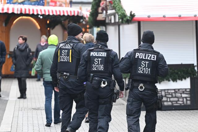 Policemen patrol past closed Christmas market shops days after a car-ramming attack on the Christmas market in Magdeburg, eastern Germany, on December 23, 2024. Magdeburg has been in deep mourning over the mass carnage on Friday evening, December 20, 2024, when an SUV smashed through a crowd at its Christmas market, killing four women and a nine-year-old child and injuring 205 people. Political pressure has built on the question of potential missed warnings about Saudi suspect Taleb al-Abdulmohsen, a 50-year-old psychiatrist who had made online deaths threats and previously had trouble with the law. (Photo by RALF HIRSCHBERGER / AFP)