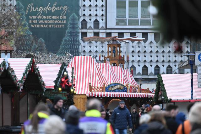 People walk past closed Christmas market shops days after a car-ramming attack on the Christmas market in Magdeburg, eastern Germany, on December 23, 2024. Magdeburg has been in deep mourning over the mass carnage on Friday evening, December 20, 2024, when an SUV smashed through a crowd at its Christmas market, killing four women and a nine-year-old child and injuring 205 people. Political pressure has built on the question of potential missed warnings about Saudi suspect Taleb al-Abdulmohsen, a 50-year-old psychiatrist who had made online deaths threats and previously had trouble with the law. (Photo by RALF HIRSCHBERGER / AFP)