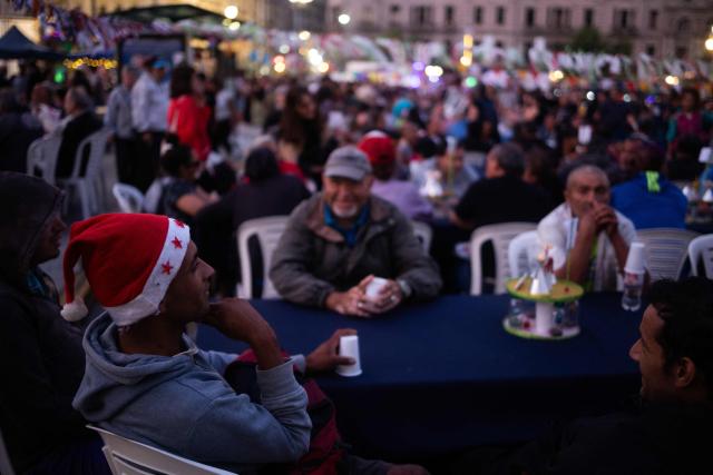 A group of people talk as they take part in a Christmas solidarity dinner called 'No Families Without Christmas' in front of the National Congress in Buenos Aires on December 24, 2024. A Christmas solidarity dinner for the homeless gathered in Buenos Aires some three thousand people in front of the National Congress when poverty reaches more than half of the Argentine population after the first year of Javier Milei's ultra-liberal government. (Photo by TOMAS CUESTA / AFP)