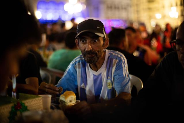 A man looks on as he takes part in a Christmas solidarity dinner called 'No Families Without Christmas' in front of the National Congress in Buenos Aires on December 24, 2024. A Christmas solidarity dinner for the homeless gathered in Buenos Aires some three thousand people in front of the National Congress when poverty reaches more than half of the Argentine population after the first year of Javier Milei's ultra-liberal government. (Photo by TOMAS CUESTA / AFP)