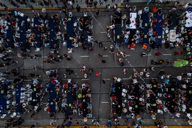 Aerial view showing volunteers and homeless people taking part in a Christmas solidarity dinner called 'No Families Without Christmas' in front of the National Congress in Buenos Aires on December 24, 2024. A Christmas solidarity dinner for the homeless gathered in Buenos Aires some three thousand people in front of the National Congress when poverty reaches more than half of the Argentine population after the first year of Javier Milei's ultra-liberal government. (Photo by TOMAS CUESTA / AFP)