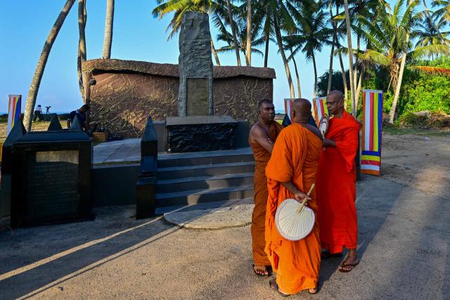 Sri Lankan Buddhist monks stand beside a memorial for those who lost their lives in the 2004 Indian Ocean tsunami, in Peraliya on December 26, 2024, the 20th anniversary of the disaster. On December 26, 2004, a magnitude 9.1 earthquake struck the coast of Sumatra in Indonesia and triggered a huge tsunami across the Indian Ocean that killed more than 220,000 people in a dozen countries. (Photo by Ishara S. KODIKARA / AFP)