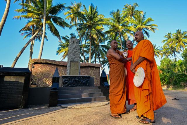 TOPSHOT - Sri Lankan Buddhist monks stand beside a memorial for those who lost their lives in the 2004 Indian Ocean tsunami, in Peraliya on December 26, 2024, the 20th anniversary of the disaster. On December 26, 2004, a magnitude 9.1 earthquake struck the coast of Sumatra in Indonesia and triggered a huge tsunami across the Indian Ocean that killed more than 220,000 people in a dozen countries. (Photo by Ishara S. KODIKARA / AFP)