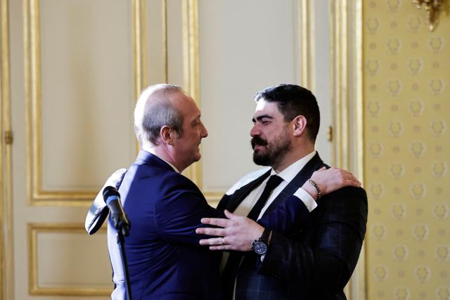 Newly-appointed French Minister of Public Action, Civil Service and Simplification Laurent Marcangeli (L) embraces outgoing French Minister of Civil Service, Streamlining, and Public Sector Transformation Guillaume Kasbarian during a handover ceremony, in Paris, on December 26, 2024. (Photo by STEPHANE DE SAKUTIN / AFP)