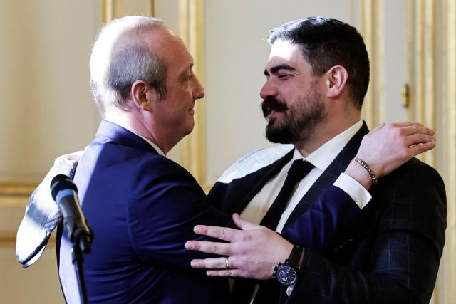 Newly-appointed French Minister of Public Action, Civil Service and Simplification Laurent Marcangeli (L) embraces outgoing French Minister of Civil Service, Streamlining, and Public Sector Transformation Guillaume Kasbarian during a handover ceremony, in Paris, on December 26, 2024. (Photo by STEPHANE DE SAKUTIN / AFP)