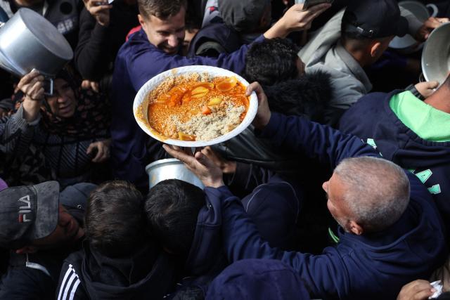 A man carries a plate of food as Palestinians collect humanitarian aid in al-Shati camp near Gaza City, on December 26, 2024, amid the ongoing war between Israel and the Palestinian Hamas movement. (Photo by Omar AL-QATTAA / AFP)