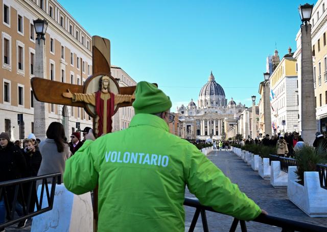 A Jubilee's volunteer holds a wooden cross on the via della Conciliazione which leads to the Vatican and St Peter's basilica, during the Catholic Jubilee Year, on December 26, 2024 in Rome. (Photo by Tiziana FABI / AFP)