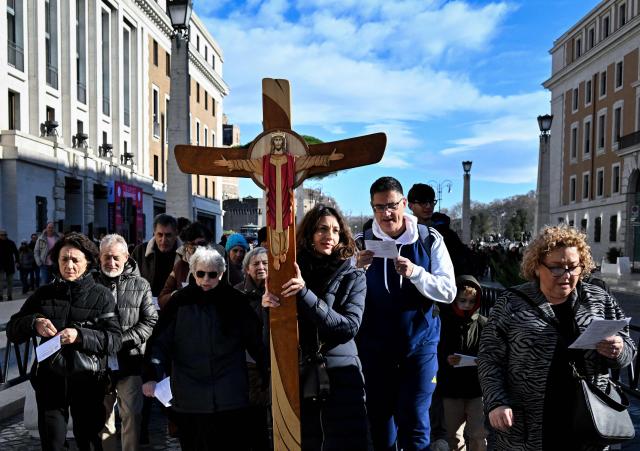 Pilgrims carry a cross on the via della Conciliazione which leads to the Vatican and St Peter's basilica, during the Catholic Jubilee Year, on December 26, 2024 in Rome. (Photo by Tiziana FABI / AFP)