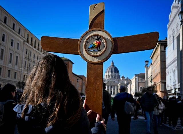 Pilgrims carry a cross on the via della Conciliazione which leads to the Vatican and St Peter's basilica, during the Catholic Jubilee Year, on December 26, 2024 in Rome. (Photo by Tiziana FABI / AFP)