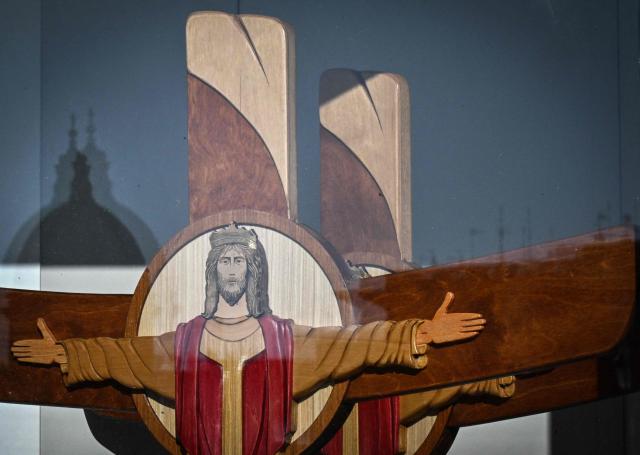 The dome of a church reflects itself on a window of the info point for pilgrims hosting wooden crosses at Piazza Pia near the via della Conciliazione which leads to the Vatican and St Peter's basilica, during the Catholic Jubilee Year, on December 26, 2024 in Rome. (Photo by Tiziana FABI / AFP)