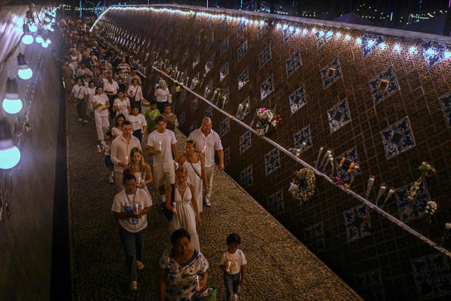 Mourners hold candles as they walk through the Ban Nam Khem Tsunami Memorial Park wall in the southern Thai province of Phang Nga on December 26, 2024. Emotional ceremonies began across Asia on December 26 to remember the 220,000 people who died two decades ago when a tsunami devastated coastal areas around the Indian Ocean, in one of the worst natural disasters in human history. (Photo by Lillian SUWANRUMPHA / AFP)