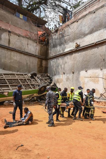 Military firefighters evacuate injured passengers from the accident site where an Abidjan Transport Company (SOTRA) bus fell into a construction site in the Plateau business district of Abidjan on December 26, 2024. (Photo by Sia KAMBOU / AFP)