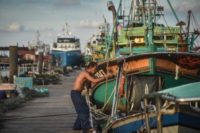 A fishman repairs a boat at Pulau Duyong Jetty in Kuala Terengganu on December 26, 2024. (Photo by ARIF KARTONO / AFP)