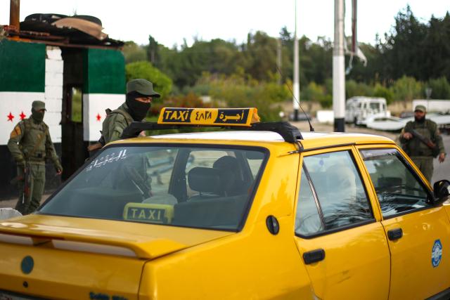 Fighters affiliated with Syria's new administration stop a car for inspection at a checkpoint in Syria's western coastal city of Latakia on December 26, 2024. Syria's new authorities launched an operation in a stronghold of ousted president Bashar al-Assad on December 26, with a war monitor saying three gunmen affiliated with the former government were killed, a day after angry protests erupted in several areas around Syria over a video showing an attack on an Alawite shrine that circulated online. (Photo by Aaref WATAD / AFP)