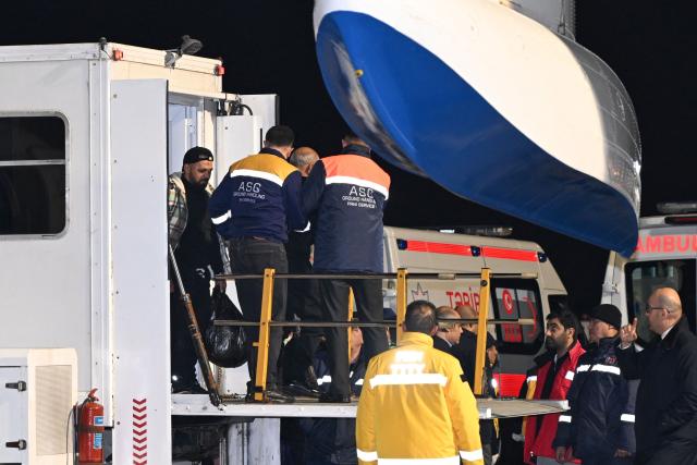 Airport ground staff amd medics assist Azerbaijani citizens, who survived the crash of the Azerbaijan Airlines' Embraer 190 passenger jet near the western Kazakh city of Aktau, upon arrival at Baku's Heydar Aliyev International Airport on December 26, 2024. (Photo by STRINGER / AFP)