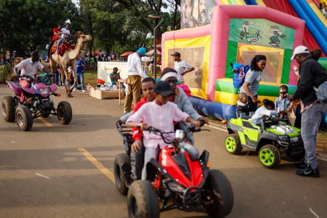 People ride on quad bikes and a camel on Boxing Day in Uhuru Park, Nairobi, on December 26, 2024. (Photo by SIMON MAINA / AFP)