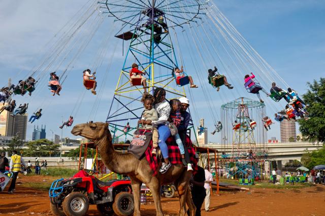 Children ride on a camel near Uhuru Park on Boxing Day, in Nairobi, on December 26, 2024. (Photo by SIMON MAINA / AFP)