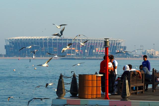 People sit on the promenade facing the 974 stadium in Doha on December 26, 2024. (Photo by KARIM JAAFAR / AFP)