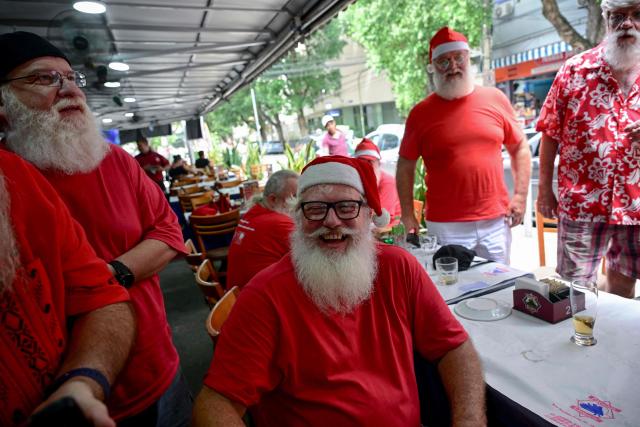 A group of professional Santas from Brazil's Santa Claus School talk during an annual event called "Barbas de Molho" (Beards at Rest) at a restaurant in Rio de Janeiro, Brazil, on December 26, 2024. The meeting is a tradition of the group to celebrate the end of the Christmas season. (Photo by Mauro PIMENTEL / AFP)