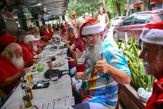 A professional Santa Claus from Brazil's Santa Claus School drinks a caipirinha during an annual event called "Barbas de Molho" (Beards at Rest) at a restaurant in Rio de Janeiro, Brazil, on December 26, 2024. The meeting is a tradition of the group to celebrate the end of the Christmas season. (Photo by Mauro PIMENTEL / AFP)