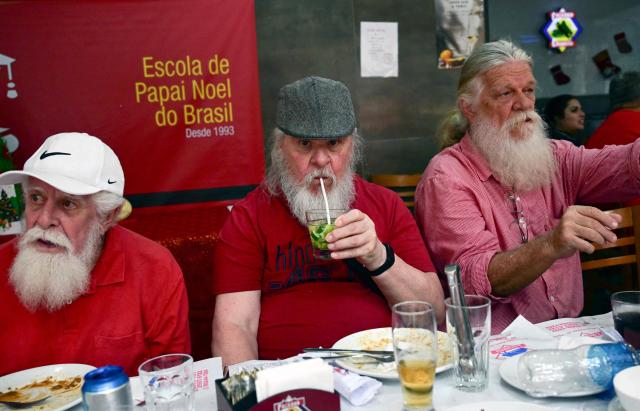 A professional Santa Claus from Brazil's Santa Claus School drinks a caipirinha during an annual event called "Barbas de Molho" (Beards at Rest) at a restaurant in Rio de Janeiro, Brazil, on December 26, 2024. The meeting is a tradition of the group to celebrate the end of the Christmas season. (Photo by Mauro PIMENTEL / AFP)