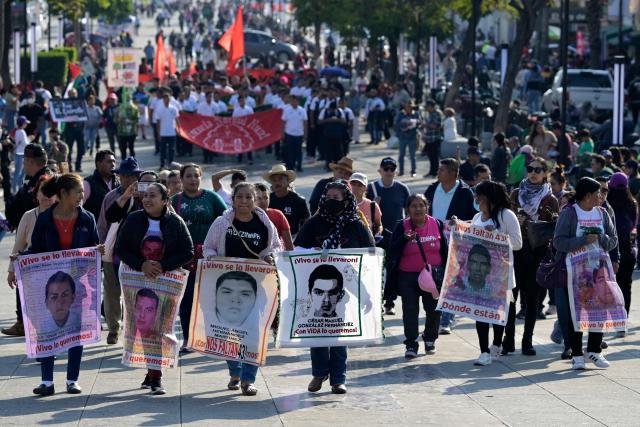 Relatives of the Ayotzinapa victims hold portraits of the missing students as they take part in a pilgrimage in front of the Basilica of Our Lady of Guadalupe to demand justice in the case of the Ayotzinapa missing students in Mexico City on December 26, 2024. 26 September marked 10 years since the enforced disappearance of 43 students from the Ayotzinapa Rural Normal School. (Photo by ALFREDO ESTRELLA / AFP)