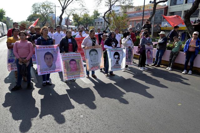 Relatives of the Ayotzinapa victims hold portraits of the missing students as they take part in a pilgrimage in front of the Basilica of Our Lady of Guadalupe to demand justice in the case of the Ayotzinapa missing students in Mexico City on December 26, 2024. 26 September marked 10 years since the enforced disappearance of 43 students from the Ayotzinapa Rural Normal School. (Photo by ALFREDO ESTRELLA / AFP)