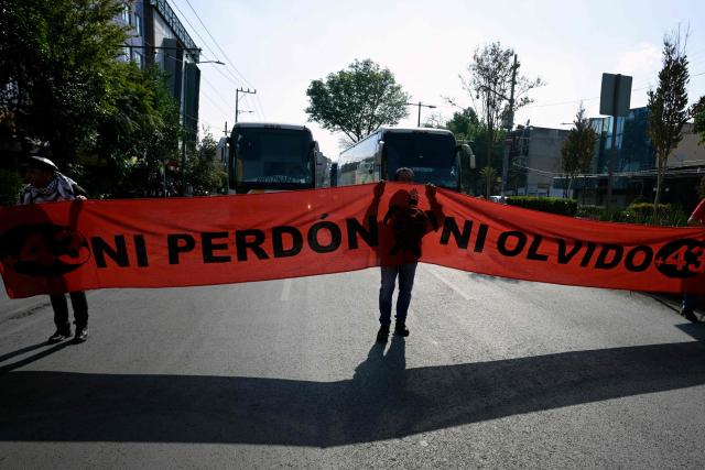 Relatives of the Ayotzinapa victims hold a banner that reads in spanish 'No forgiveness, no forgetting,' as they take part in a pilgrimage in front of the Basilica of Our Lady of Guadalupe to demand justice in the case of the Ayotzinapa missing students in Mexico City on December 26, 2024. 26 September marked 10 years since the enforced disappearance of 43 students from the Ayotzinapa Rural Normal School. (Photo by ALFREDO ESTRELLA / AFP)