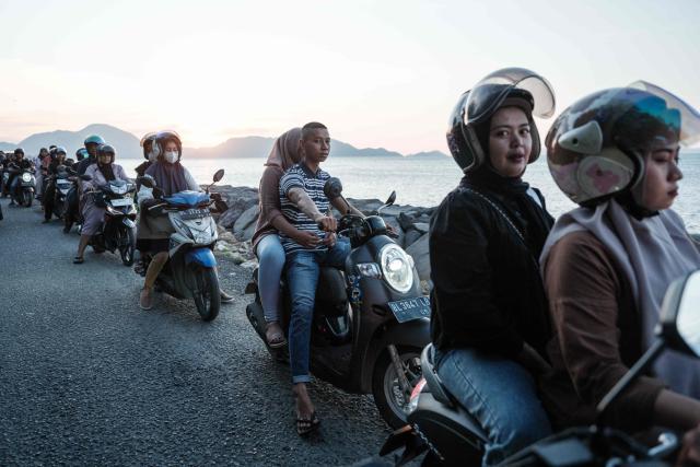 People ride scooters along the seaside in Banda Aceh on December 26, 2024.  (Photo by Yasuyoshi CHIBA / AFP)