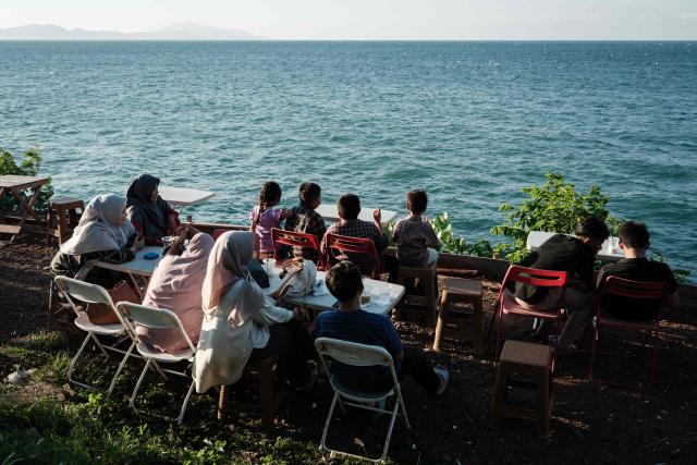 People spend time by the seaside during sunset in Banda Aceh on December 26, 2024.  (Photo by Yasuyoshi CHIBA / AFP)