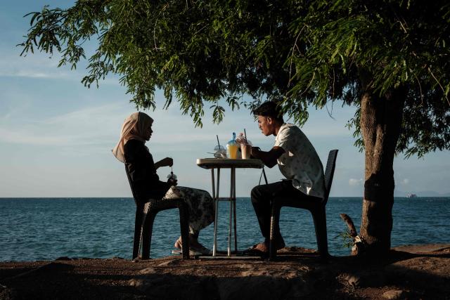 People spend time by the seaside during sunset in Banda Aceh on December 26, 2024.  (Photo by Yasuyoshi CHIBA / AFP)