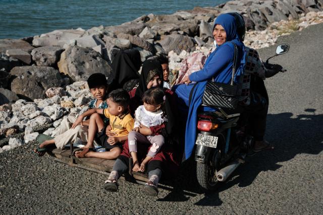 People ride a modified scooter along the seaside in Banda Aceh on December 26, 2024.  (Photo by Yasuyoshi CHIBA / AFP)