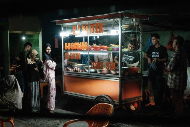 People wait for ordered food at a food stall in Banda Aceh on December 26, 2024. (Photo by Yasuyoshi CHIBA / AFP)