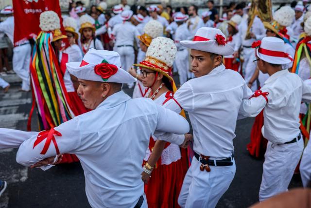 A group of men grab each other's elbows as they take part in the cultural and religious celebration Marujada, a traditional festival that pays homage to Saint Benedict (Sao Benedito) in the city of Bragança, Para State, Brazil, on December 26, 2024. Cultural heritage of Brazil, the Marujada is a traditional festival that pays homage to Saint Benedict, the "black saint," and has one of its highlights on Christmas Day, during the feast that lasts nine days until December 26. (Photo by Anderson Coelho / AFP)