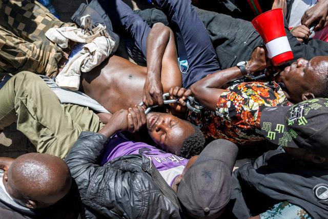 Anti-riot police attempt to break up and arrest protesters braced on the ground in a stand off during protests to demand the release of those allegedly abducted by state security agencies in Nairobi on December 30, 2024. Security forces in the East African nation have been accused of carrying out dozens of illegal detentions since youth-led anti-government demonstrations in June and July. Kenyan President William Ruto has promised an end to abductions, following the latest spate of disappearances that have been condemned by rights groups, lawyers and politicians. (Photo by Tony KARUMBA / AFP)