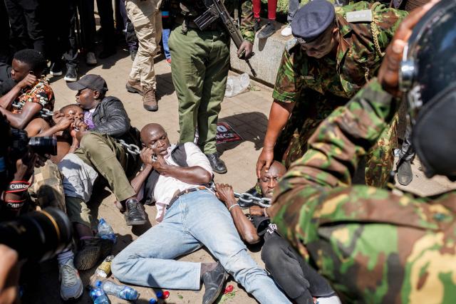 Anti-riot police attempt to break up and arrest protesters braced on the ground in a stand off during protests to demand the release of those allegedly abducted by state security agencies in Nairobi on December 30, 2024. Security forces in the East African nation have been accused of carrying out dozens of illegal detentions since youth-led anti-government demonstrations in June and July. Kenyan President William Ruto has promised an end to abductions, following the latest spate of disappearances that have been condemned by rights groups, lawyers and politicians. (Photo by Tony KARUMBA / AFP)