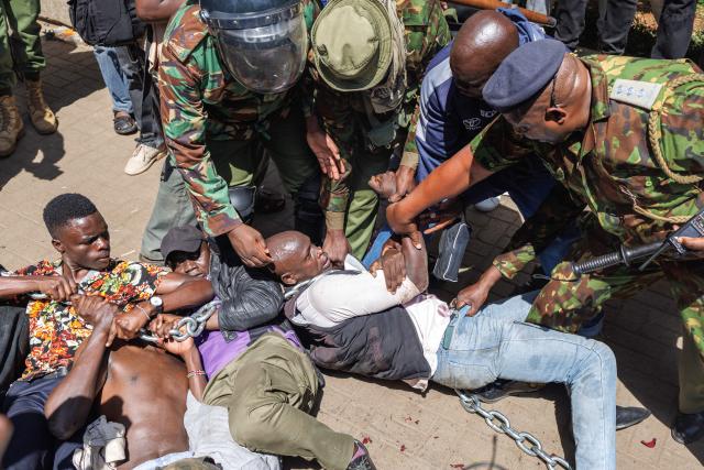 Anti-riot police attempt to break up and arrest protesters braced on the ground in a stand off during protests to demand the release of those allegedly abducted by state security agencies in Nairobi on December 30, 2024. Security forces in the East African nation have been accused of carrying out dozens of illegal detentions since youth-led anti-government demonstrations in June and July. Kenyan President William Ruto has promised an end to abductions, following the latest spate of disappearances that have been condemned by rights groups, lawyers and politicians. (Photo by Tony KARUMBA / AFP)