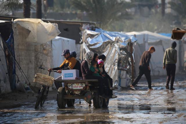 People ride in an animal-pulled cart at a flooded road following heavy rain at an internally displaced peoples' camp in Deir el-Balah in the central Gaza Strip on December 30, 2024, amid the ongoing war in the Palestinian territory between Israel and Hamas. (Photo by Eyad BABA / AFP)