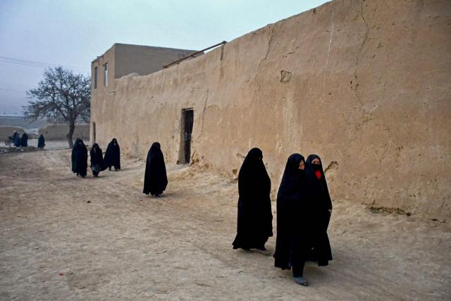 Afghan women walk along a roadside early morning on the outskirts of Mazar-i-Sharif on December 30, 2024. (Photo by Atif ARYAN / AFP)