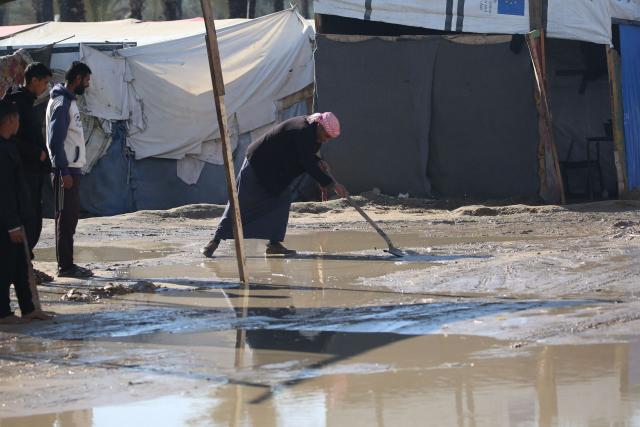 A man uses a shovel in a flood area following heavy rain at an internally displaced peoples' camp in Deir el-Balah in the central Gaza Strip on December 30, 2024, amid the ongoing war in the Palestinian territory between Israel and Hamas. (Photo by Eyad BABA / AFP)