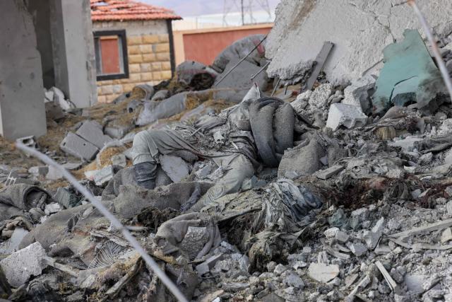 EDITORS NOTE: Graphic content / TOPSHOT - The body of a man lies at the site of an explosion at a weapons depot the previous day at the Industrial area of Adra, some 30 kilometres from the Syrian capital Damascus on December 30, 2024. An official from a nearby area, requesting anonymity, told AFP on December 29 that "an explosion of unknown origin" rocked the Adra industrial area, reporting an unspecified number of casualties and adding that rescue operations were ongoing. (Photo by ANWAR AMRO / AFP)