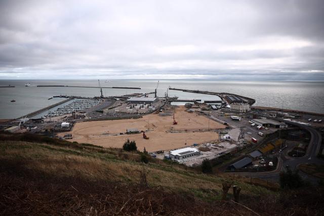 Construction vehicles are pictured parked on sand, that has been used to fill docks at the harbour at the Port of Dover, on the southeast coast of England on December 30, 2024. (Photo by HENRY NICHOLLS / AFP)