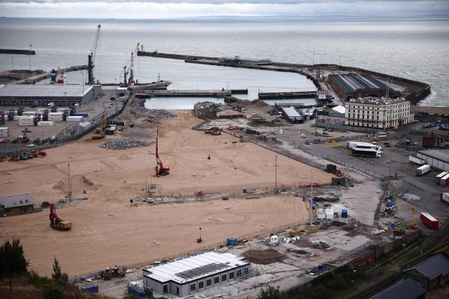 Construction vehicles are pictured parked on sand, that has been used to fill docks at the harbour at the Port of Dover, on the southeast coast of England on December 30, 2024. (Photo by HENRY NICHOLLS / AFP)