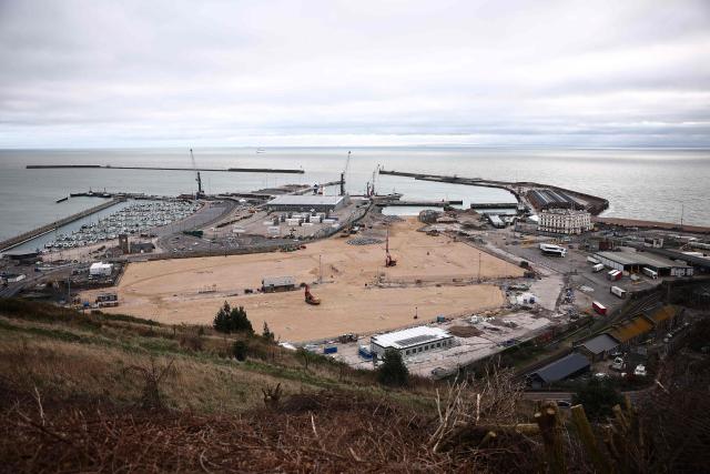 Construction vehicles are pictured parked on sand, that has been used to fill docks at the harbour at the Port of Dover, on the southeast coast of England on December 30, 2024. (Photo by HENRY NICHOLLS / AFP)