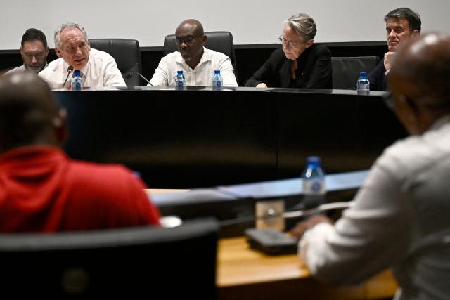 French Prime Minister Francois Bayrou (2L) attends with France's Minister of Education, Higher Education and Research Elisabeth Borne (2R) and France's Minister of Overseas Manuel Valls (R) a meeting with President of the Departmental Council of Mayotte Ben Issa Ousseni (C) and local officials to present his plan at the departmental council in Mamoudzou on the French Indian Ocean territory of Mayotte, on December 30, 2024. The most devastating cyclone to hit Mayotte in 90 years caused colossal damage on December 14, 20274 in France's poorest department, where relief workers have struggled since then to restore essential services such as water, electricity and communications networks. (Photo by JULIEN DE ROSA / AFP)