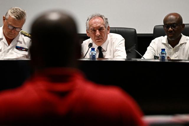 French Prime Minister Francois Bayrou (C) attends a meeting with President of the Departmental Council of Mayotte Ben Issa Ousseni (R) and local officials to present his plan at the departmental council in Mamoudzou on the French Indian Ocean territory of Mayotte, on December 30, 2024. The most devastating cyclone to hit Mayotte in 90 years caused colossal damage on December 14, 20274 in France's poorest department, where relief workers have struggled since then to restore essential services such as water, electricity and communications networks. (Photo by JULIEN DE ROSA / AFP)