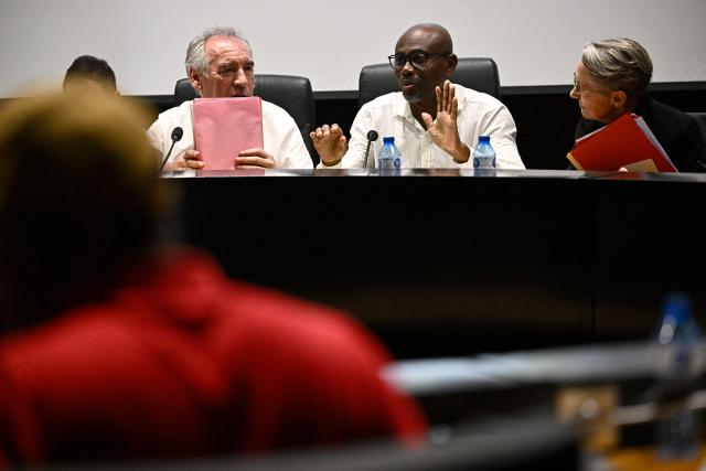 French Prime Minister Francois Bayrou (L) attends with France's Minister of Education, Higher Education and Research Elisabeth Borne (R) a meeting with President of the Departmental Council of Mayotte Ben Issa Ousseni (C-R) and local officials to present his plan at the departmental council in Mamoudzou on the French Indian Ocean territory of Mayotte, on December 30, 2024. The most devastating cyclone to hit Mayotte in 90 years caused colossal damage on December 14, 20274 in France's poorest department, where relief workers have struggled since then to restore essential services such as water, electricity and communications networks. (Photo by JULIEN DE ROSA / AFP)