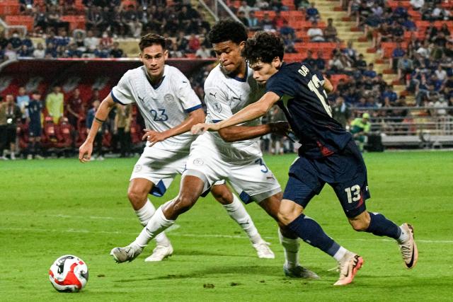 Thailand's Benjamin James Davis (R) fights for the ball with Philippines' defender Paul Tabinas (C) and Philippines' defender Christian Rontini (L) during the 2024 ASEAN Electric Cup semi-final second leg football match between Thailand and the Philippines at the Rajamangala National Stadium in Bangkok on December 30, 2024. (Photo by Amaury PAUL / AFP)