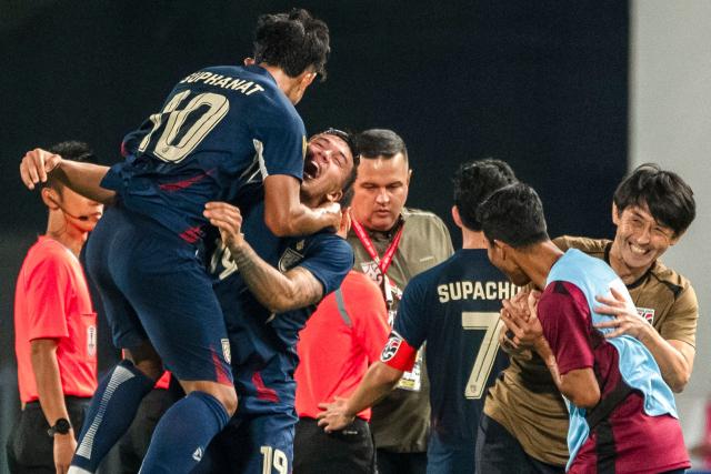 Thailand's forward Suphanat Mueanta (L) celebrates with Thailand's midfielder William Weidersjo (C), Thailand's Japanese coach Masatada Ishii (R) and teammates after winning the 2024 ASEAN Electric Cup semi-final second leg football match between Thailand and the Philippines at the Rajamangala National Stadium in Bangkok on December 30, 2024. (Photo by Chanakarn Laosarakham / AFP)